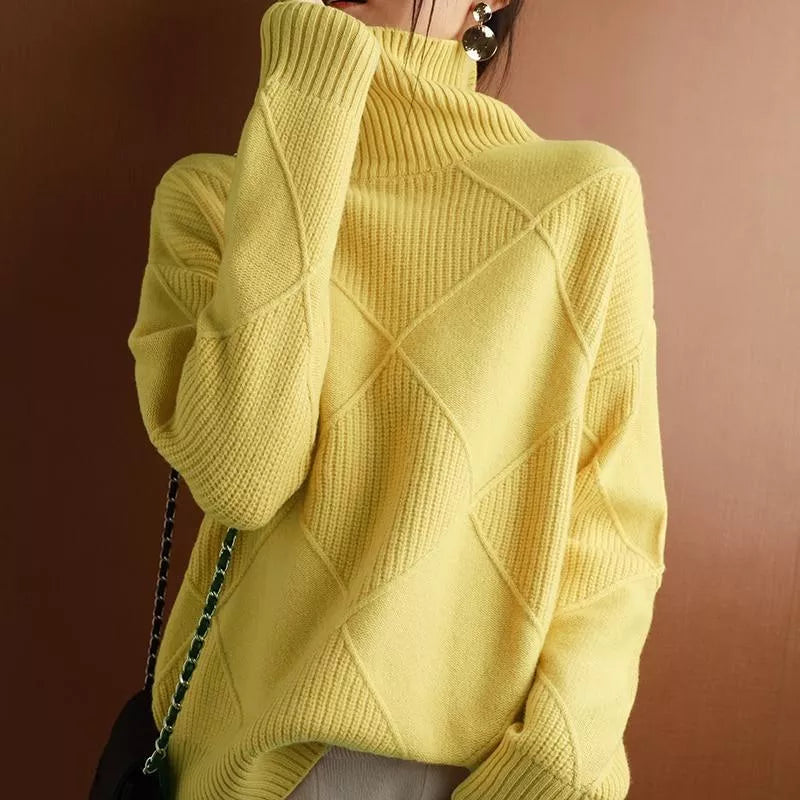 Eine Frau trägt einen schwarzen Strickpullover mit markantem Rautenmuster.